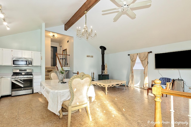 dining space with a wood stove, beamed ceiling, ceiling fan with notable chandelier, and high vaulted ceiling