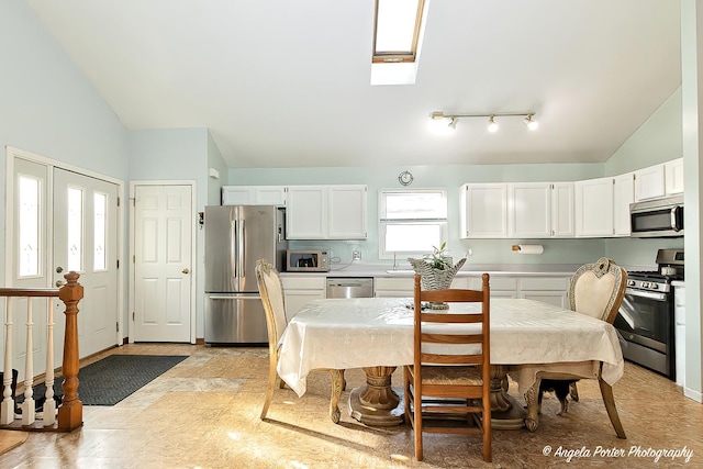 kitchen with sink, vaulted ceiling with skylight, tasteful backsplash, white cabinetry, and stainless steel appliances