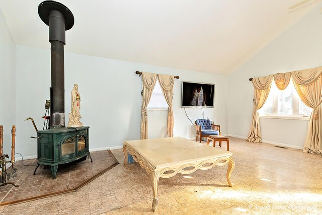 dining room featuring ceiling fan with notable chandelier, beam ceiling, a wood stove, and high vaulted ceiling