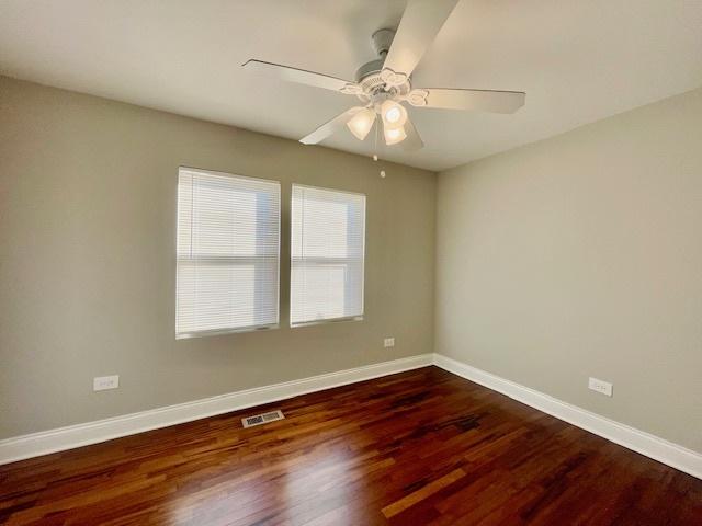 spare room with dark wood-type flooring and ceiling fan