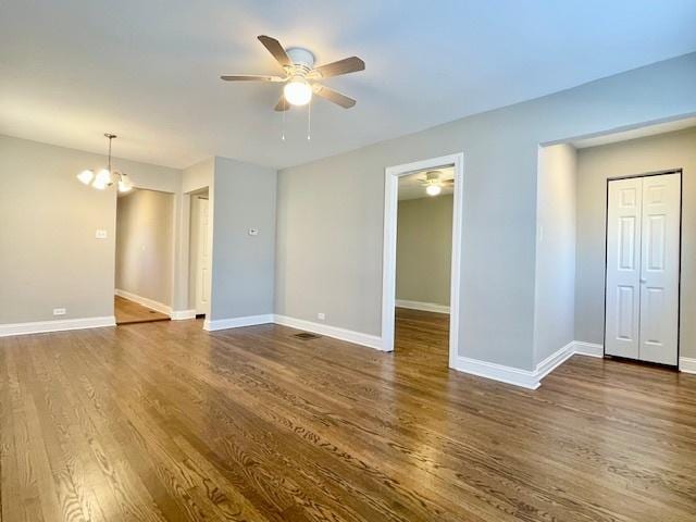 spare room with dark hardwood / wood-style flooring and ceiling fan with notable chandelier