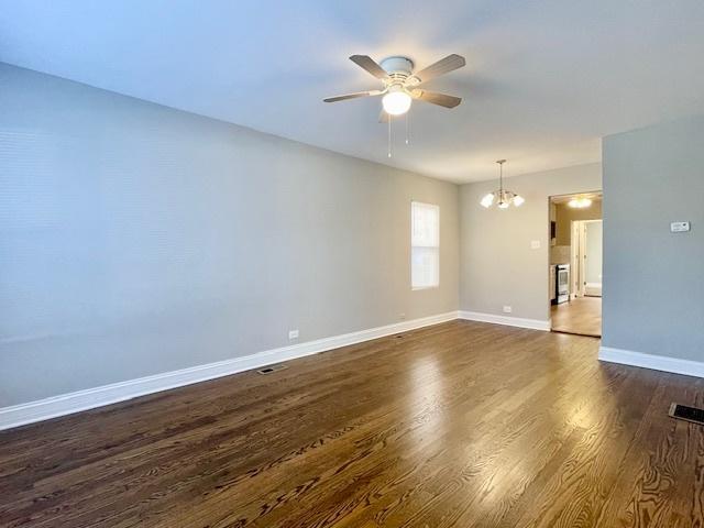 unfurnished room featuring dark wood-type flooring and ceiling fan with notable chandelier