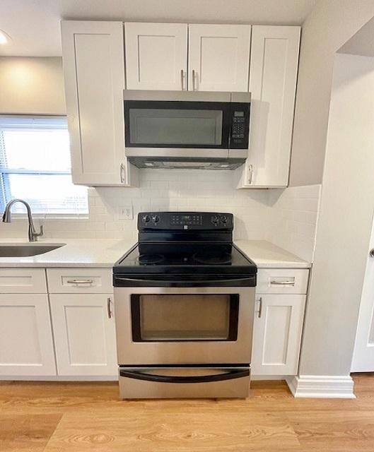 kitchen featuring stainless steel appliances, sink, light hardwood / wood-style flooring, and white cabinets