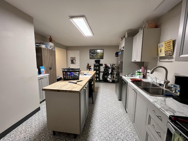 kitchen featuring wood counters, gray cabinetry, stainless steel appliances, sink, and a center island