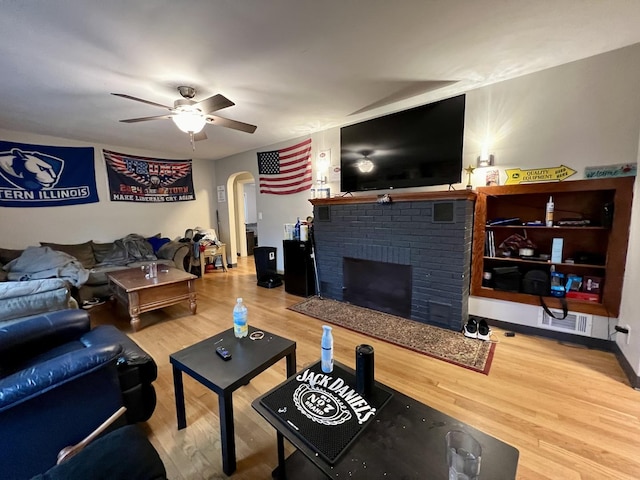 living room with hardwood / wood-style floors, a brick fireplace, and ceiling fan