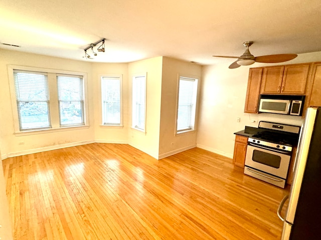 kitchen featuring ceiling fan, stove, white fridge, and light hardwood / wood-style flooring