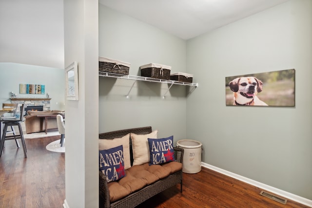 living area with a stone fireplace and dark wood-type flooring