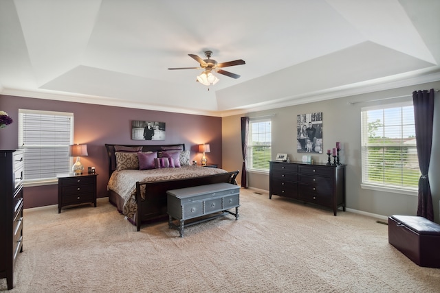 bedroom with a raised ceiling, multiple windows, ceiling fan, and light carpet