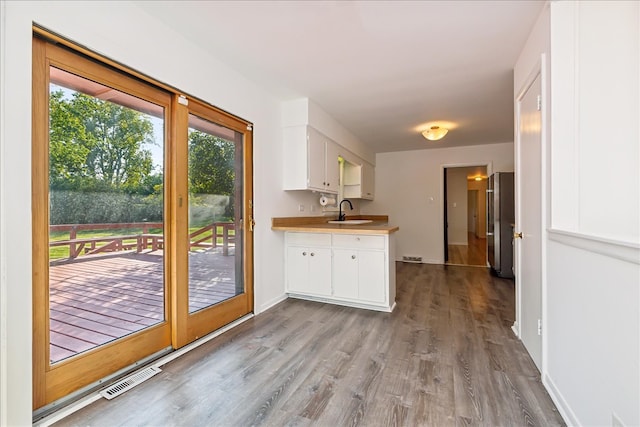 kitchen featuring white cabinetry, sink, high quality fridge, and light hardwood / wood-style flooring