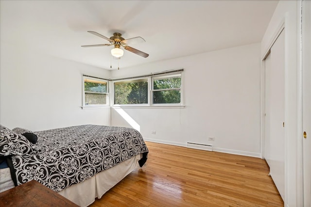 bedroom featuring ceiling fan, a closet, a baseboard radiator, and light hardwood / wood-style flooring