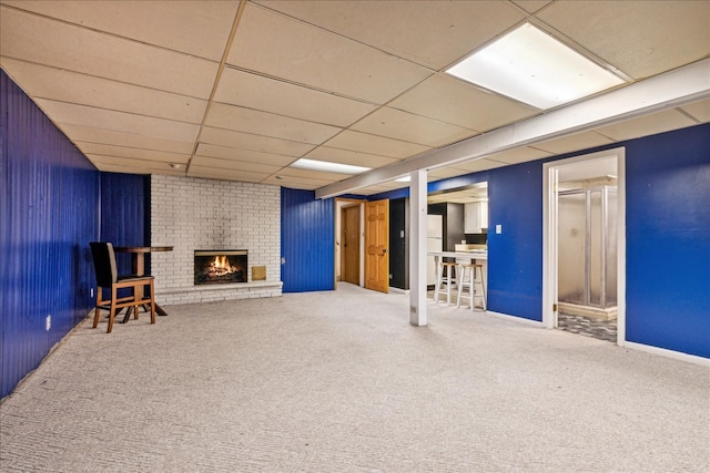 basement featuring a fireplace, carpet floors, and a drop ceiling