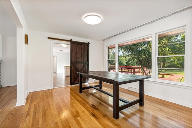 dining area with light wood-type flooring and a barn door