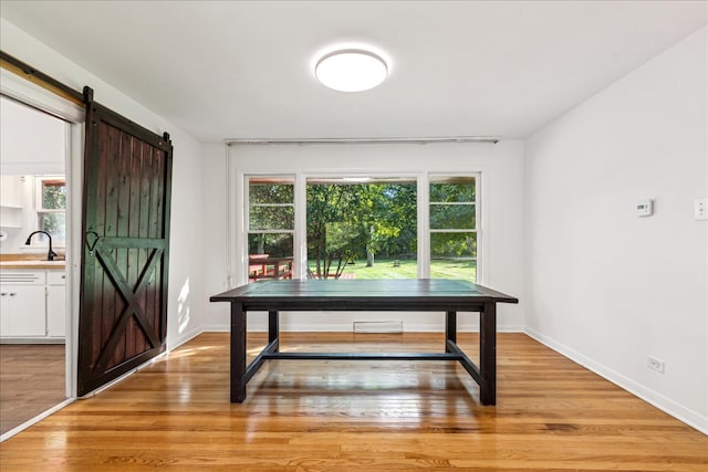 dining space with a barn door, plenty of natural light, light hardwood / wood-style floors, and sink