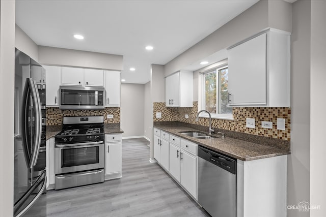 kitchen featuring sink, tasteful backsplash, light hardwood / wood-style floors, white cabinetry, and stainless steel appliances