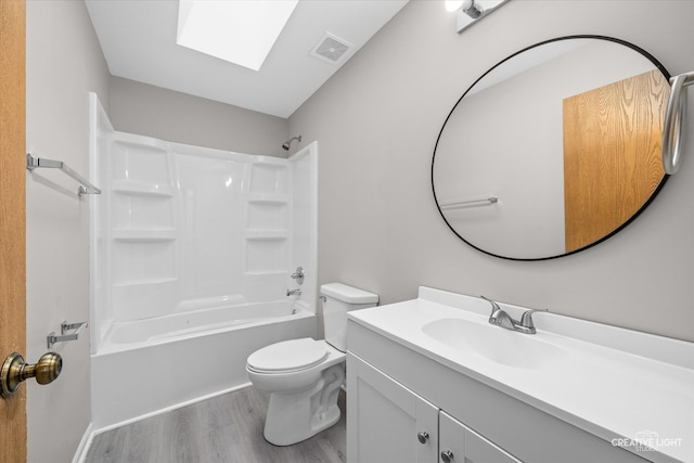 full bathroom with a skylight, bathing tub / shower combination, wood-type flooring, toilet, and vanity