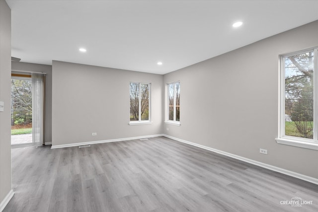 spare room with plenty of natural light and light hardwood / wood-style flooring