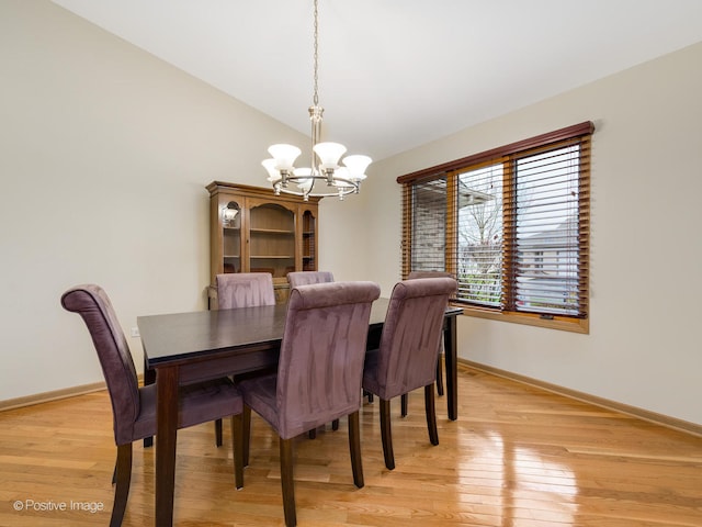 dining room featuring vaulted ceiling, light wood-type flooring, and a chandelier