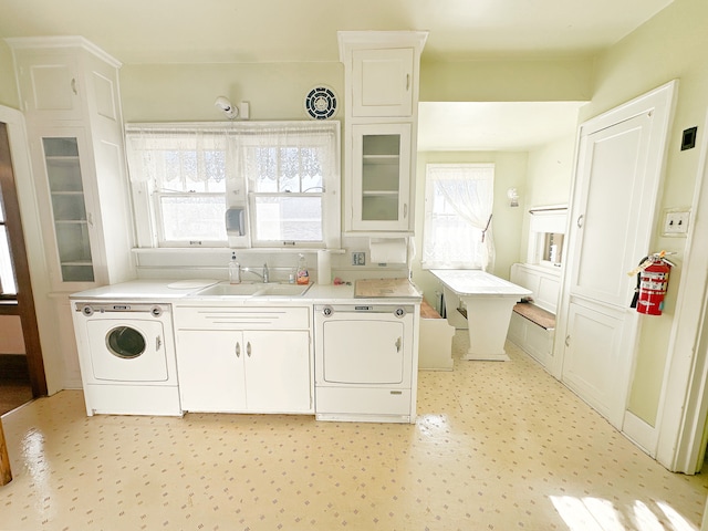 kitchen featuring white cabinetry, sink, and washer / dryer