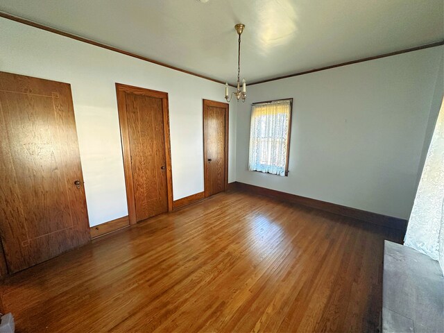 unfurnished bedroom with dark hardwood / wood-style flooring and a notable chandelier