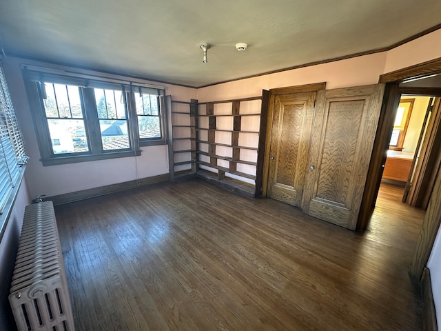 unfurnished bedroom featuring ornamental molding, dark wood-type flooring, and radiator