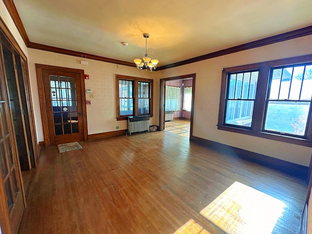 interior space featuring hardwood / wood-style floors, radiator heating unit, ornamental molding, and an inviting chandelier