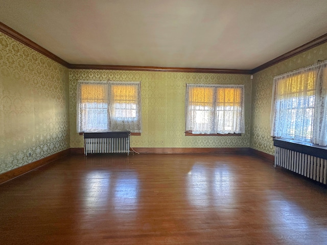 empty room with crown molding, radiator heating unit, and dark hardwood / wood-style floors