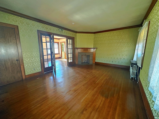 unfurnished living room with dark hardwood / wood-style floors, ornamental molding, a fireplace, and french doors