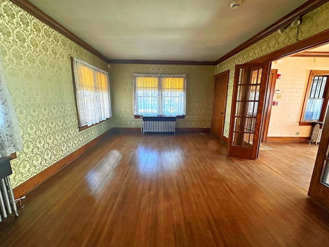 spare room with hardwood / wood-style flooring, radiator heating unit, ornamental molding, and a wealth of natural light