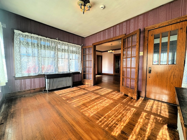 spare room with a chandelier, french doors, radiator heating unit, and hardwood / wood-style floors