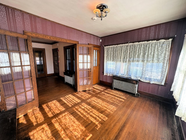 spare room with radiator heating unit, dark hardwood / wood-style floors, and a notable chandelier