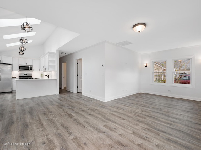 unfurnished living room featuring sink, light hardwood / wood-style floors, and vaulted ceiling with skylight