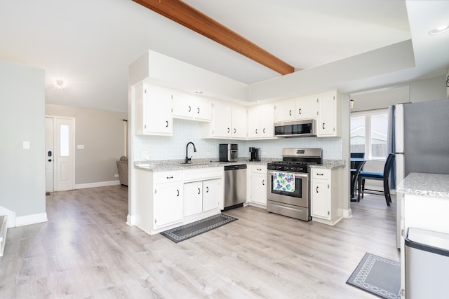 kitchen with decorative backsplash, stainless steel appliances, sink, light hardwood / wood-style flooring, and white cabinets