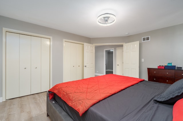 bedroom featuring light wood-type flooring and two closets