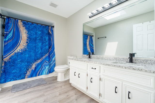 bathroom featuring vanity, hardwood / wood-style flooring, toilet, and a skylight