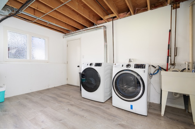 clothes washing area featuring light hardwood / wood-style floors and washing machine and clothes dryer