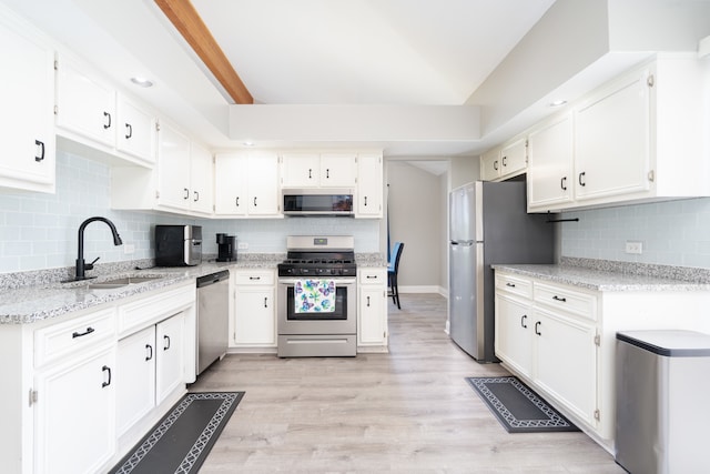 kitchen featuring white cabinets, backsplash, light wood-type flooring, and stainless steel appliances