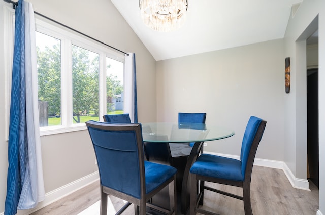 dining room featuring light hardwood / wood-style floors, lofted ceiling, and an inviting chandelier