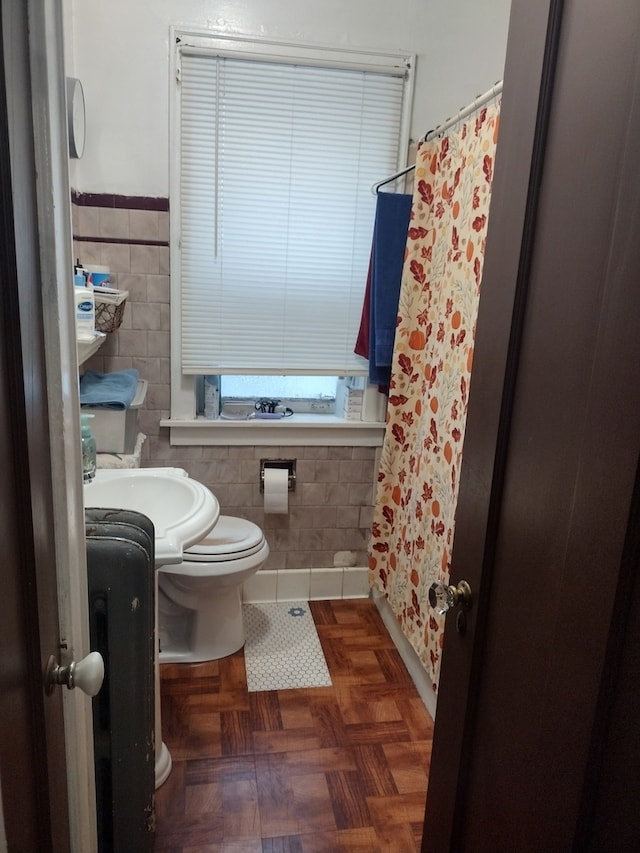 bathroom featuring sink, walk in shower, parquet flooring, toilet, and tile walls