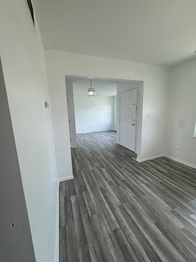 spare room featuring dark hardwood / wood-style flooring and a notable chandelier