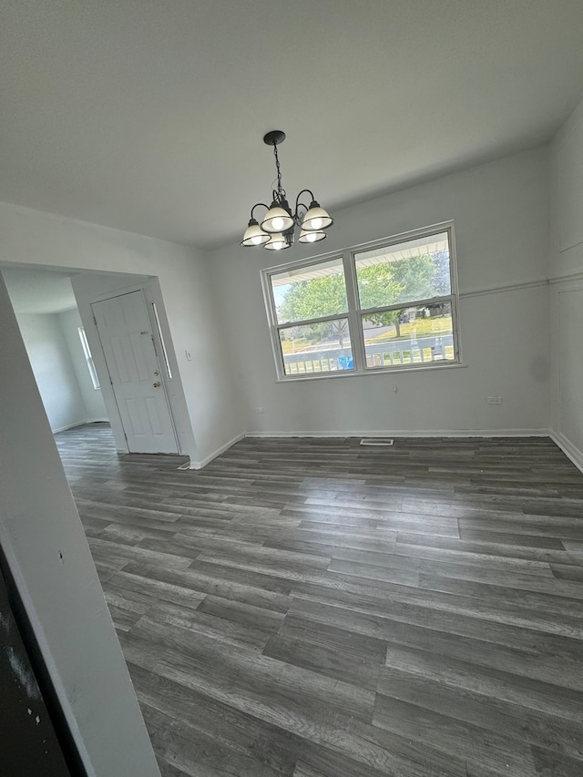 unfurnished dining area with a chandelier and dark hardwood / wood-style floors