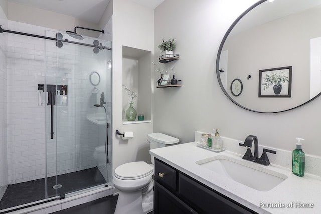 bathroom with tile patterned floors, vanity, an enclosed shower, and toilet