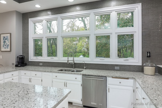 kitchen featuring dishwasher, light stone counters, white cabinetry, and sink