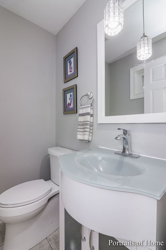 bathroom with tile patterned flooring, a notable chandelier, toilet, and sink