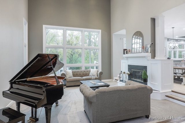 living room featuring light colored carpet, a high ceiling, and an inviting chandelier