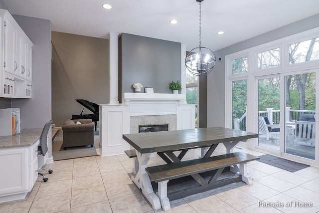 tiled dining area featuring plenty of natural light, a chandelier, and a tiled fireplace