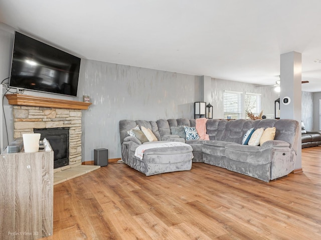 living room featuring ceiling fan, a fireplace, and hardwood / wood-style flooring