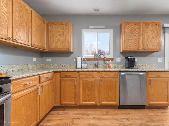 kitchen with light stone countertops, stainless steel appliances, light hardwood / wood-style floors, and sink