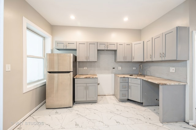 kitchen featuring gray cabinetry, sink, and stainless steel refrigerator