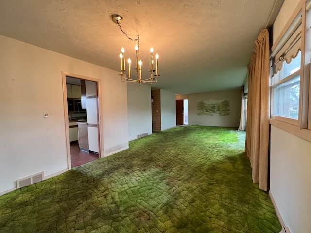 interior space with dark carpet, a textured ceiling, and an inviting chandelier