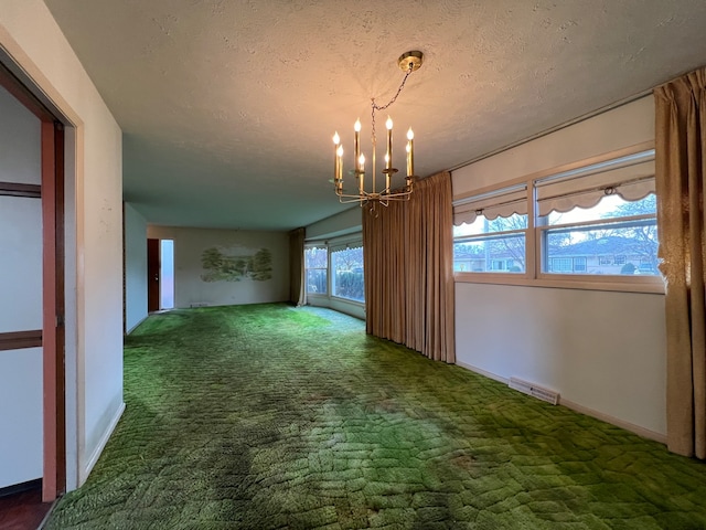 carpeted spare room with a chandelier, a textured ceiling, and a wealth of natural light